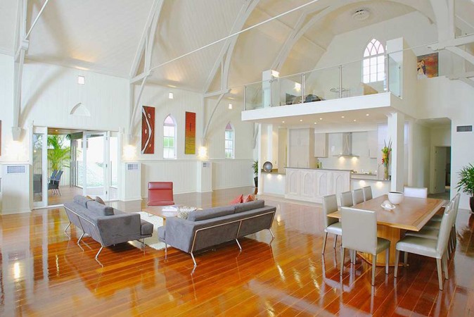 A spacious living room with hardwood floors and a vaulted ceiling in an unconventional home conversion.