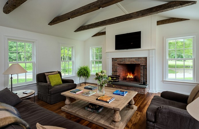 A living room with wood beams and a fireplace, inspired by Modern Farmhouse Style.