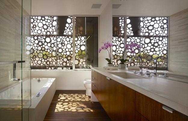 A modern bathroom with a large glass window featuring a perforated design.