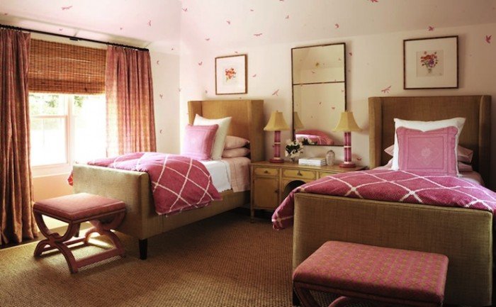 A pink bedroom with twin beds and a chair.