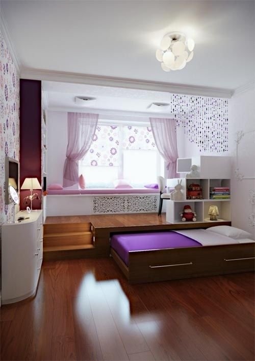 A purple and white bedroom with a space saving bed and a desk.