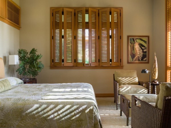 A bed in a room with decorative wooden shutters.