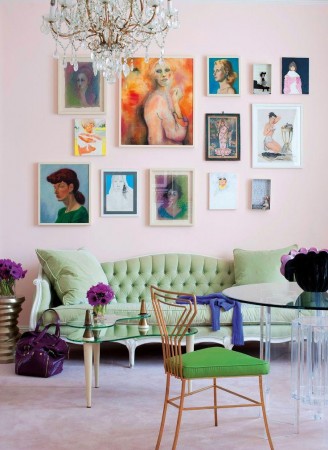 A pink living room with a green couch and a chandelier featuring alternative wall treatments.