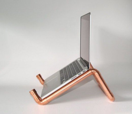 A copper pipe laptop stand with a laptop on it.