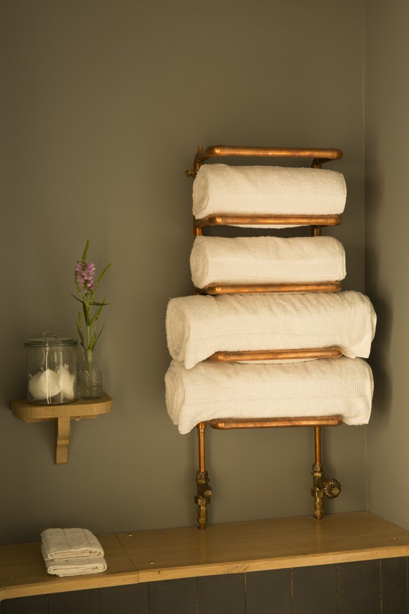 A copper pipe towel rack with towels hanging on it.