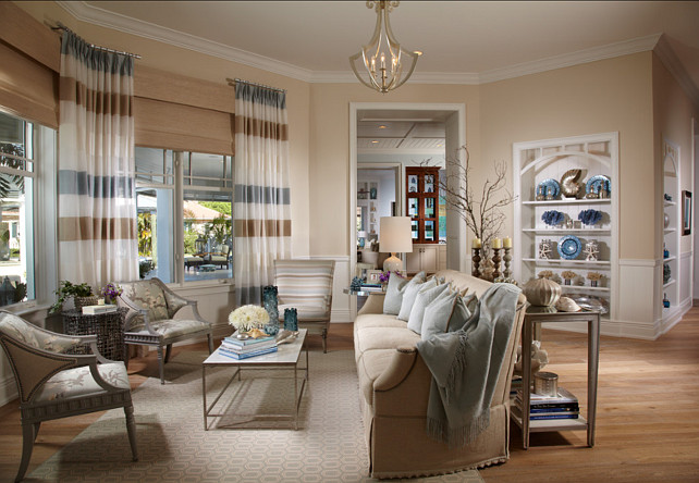 An elegant living room with understated coastal design featuring striped curtains and a coffee table.