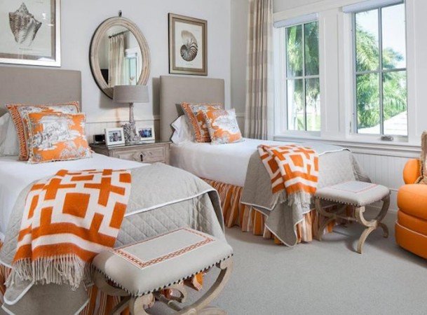 A guest room with twin beds featuring orange and gray accents.
