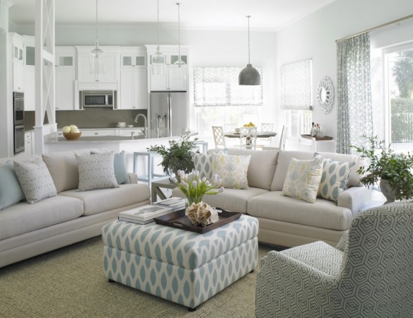 An elegant living room with understated coastal design featuring white furniture and blue accents.