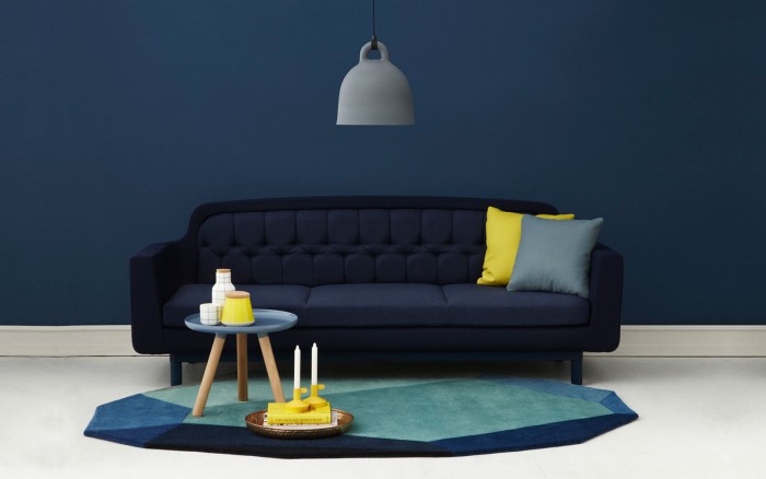 A living room with blue walls and a yellow rug, showcasing an interior design tribute to blue.