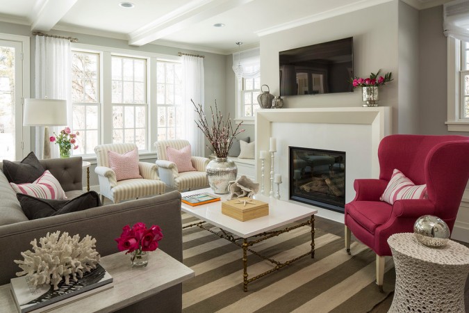 A living room with elegant pink chairs and a fireplace designed in an understated coastal style.