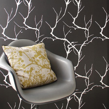 A gray chair in front of a black and white wallpaper with trendy interiors.