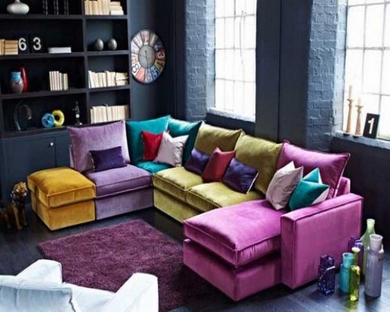 Multi-colored sectional sofa with colorful pillows plays well against dark blue walls 