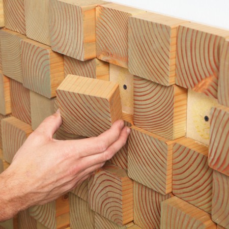 A man is using wood blocks for an alternative wall treatment.