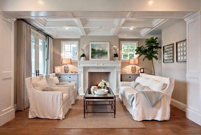 An elegant living room with understated coastal design featuring white furniture and a fireplace.