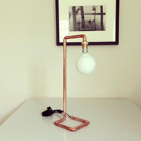 A copper lamp on a table with a picture frame.