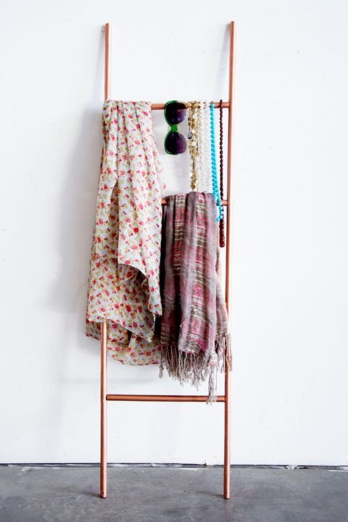 A copper pipe ladder rack with clothes hanging on it.
