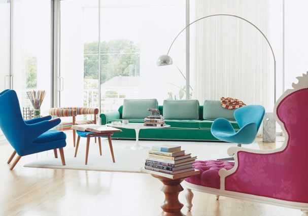 A green sofa is accompanied by blue, turquoise and fuchsia chairs