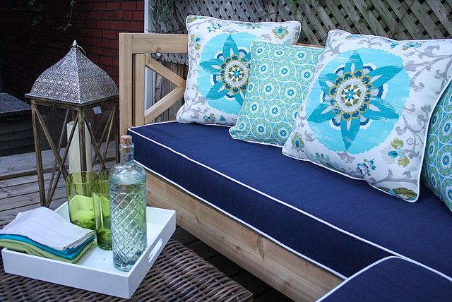 A blue couch and pillows on a wooden deck in a wonderful backyard retreat.