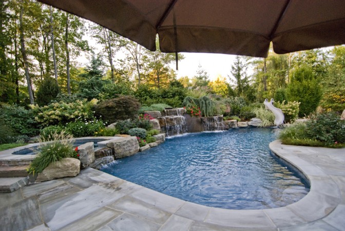 Natural stone and plantings accent this outdoor swimming pool 