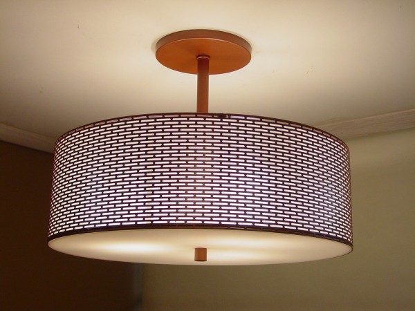 A light fixture with a perforated design and a white shade.