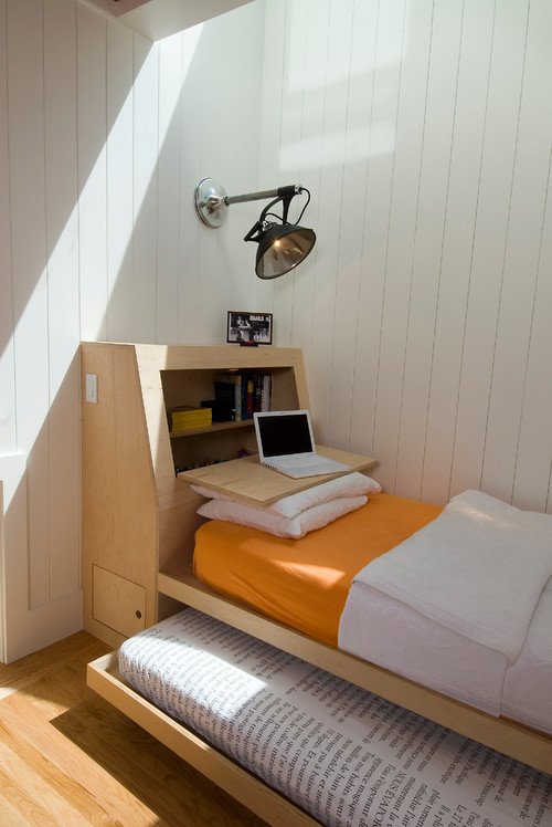 A small bedroom with a space saving bed and a desk.