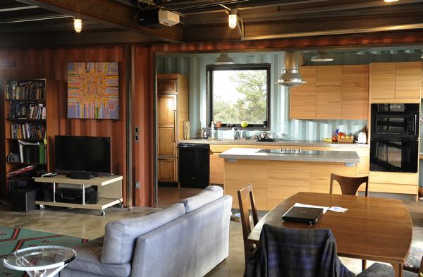 A living room, kitchen and dining room in an unconventional shipping container conversion.