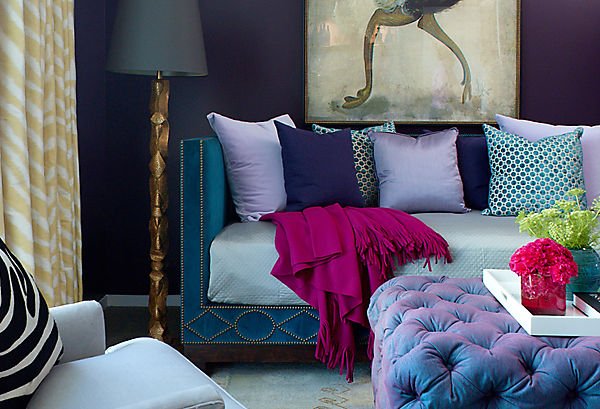 A plush blue sofa accented with amethyst pillows and ottoman