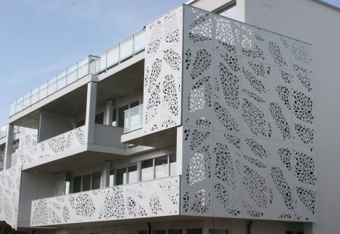 A white building with a perforated design on the side of it.