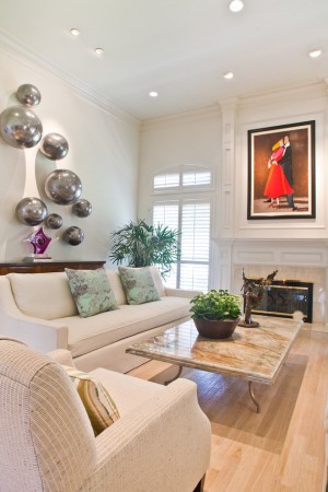 A white living room with a painting on the wall incorporates marble.