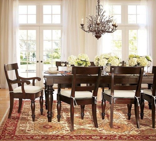 A dining room table with chairs and a rug that adds to the coziness of a house, making it feel like home.