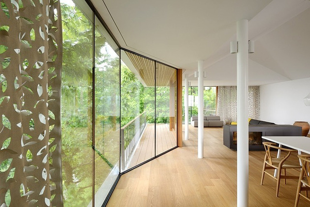 A living room with a large glass wall featuring a trendy perforated design overlooking a wooded area.