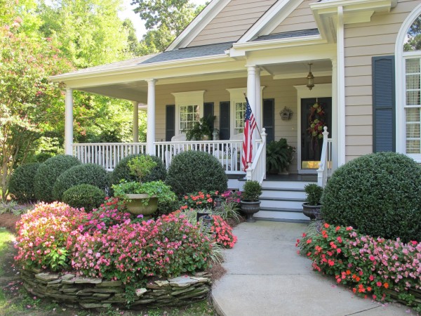 A front porch with flowers and bushes, creating a cozy home atmosphere.