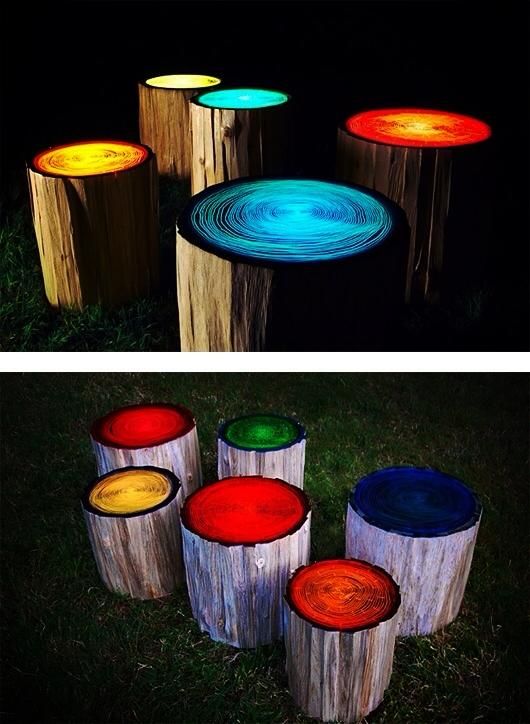 A group of different colored tree trunks with lights on them.