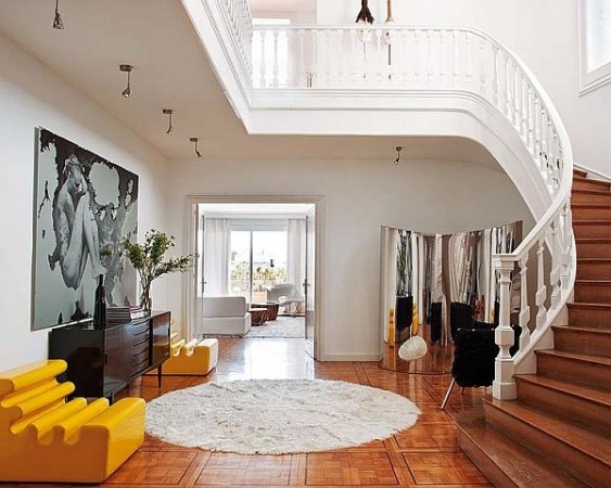 A bold entryway with a yellow rug and a staircase.
