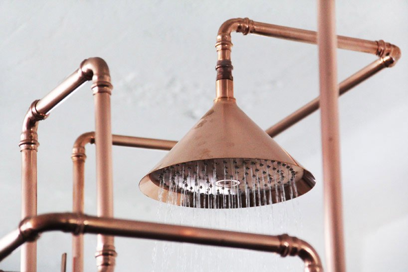 A copper shower head with pipes.