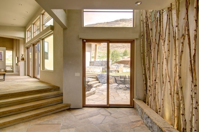A home with a stone wall and a door leading to a patio, featuring interior design trends.