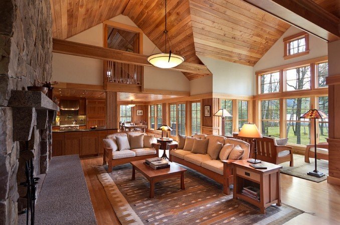 A large living room with wood beams and a stone fireplace in a lake home.