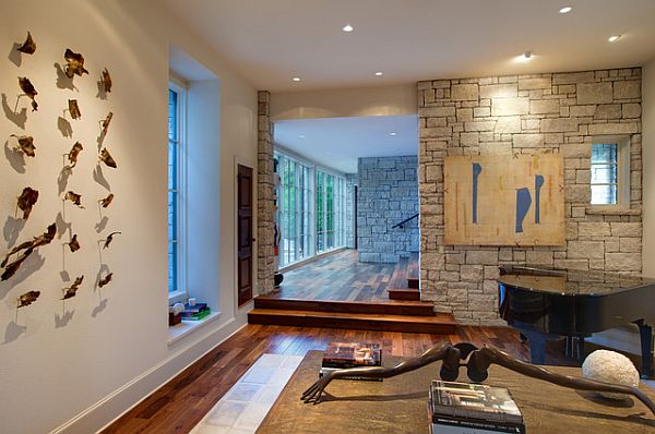 A modern living room with a piano and a stone wall.