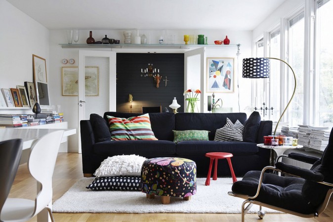 A modern living room with a black couch and a colorful rug.