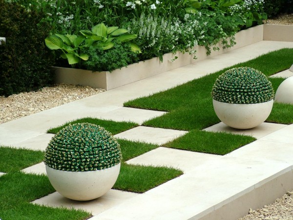 A stylish garden with white urns and green grass.