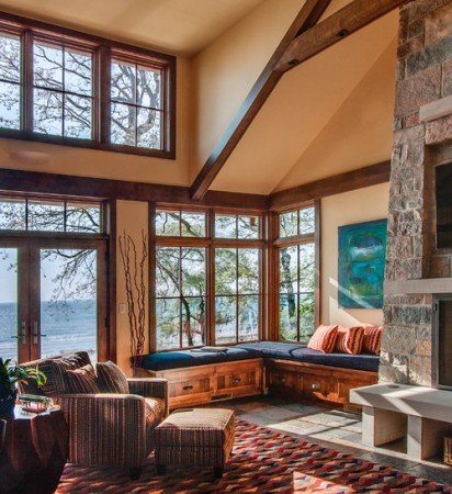 A lakefront living room with a stone fireplace, showcasing stunning lake views.