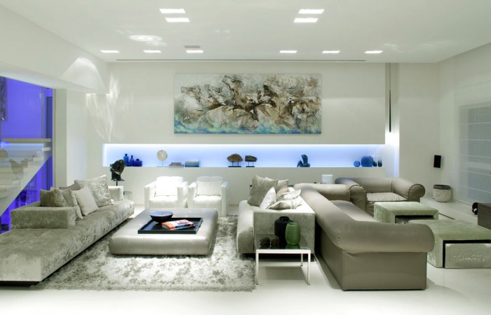 A modern living room with white furniture and blue lighting.