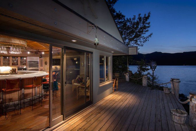 A deck with a bar overlooking a lake at night in a Lake Home.