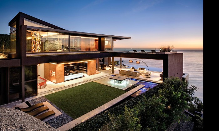 A modern house with stylish outdoor spaces overlooking the ocean at dusk.