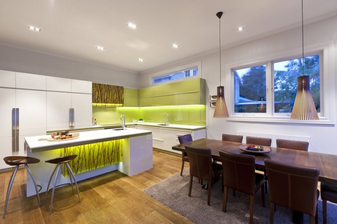 A modern white kitchen with green accents.