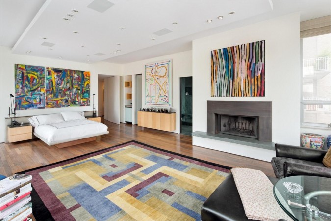 A modern bedroom with a fireplace and a colorful rug for art lovers.