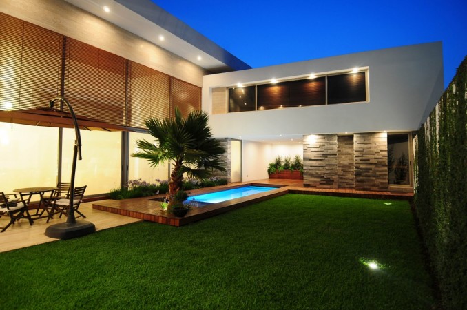 A stylish modern house with a pool and lawn, perfect for outdoor living.