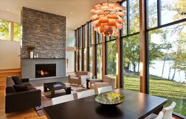 A modern living room with large windows and a fireplace in a Lake Home.