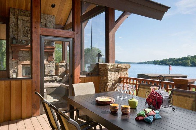 A lakeside deck with a table and chairs overlooking a tranquil lake.