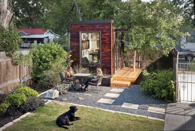 A small backyard with two people and a dog that breaks the mold.
